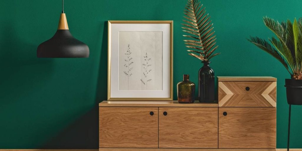 Salone stile scandinavo con parete verde e mobile di legno con vasi e piante.