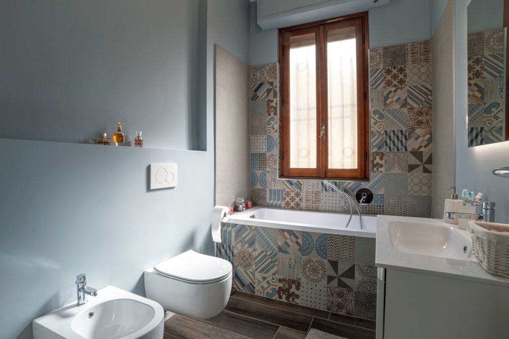 Bagno moderno con sanitari bianchi a sospensione e rivestimenti in cementine