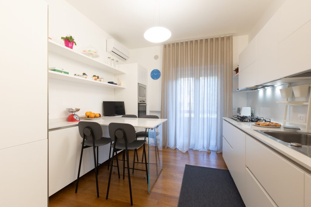 Cucina bianca stile moderno con penisola con sgabelli alti grigio scuro.