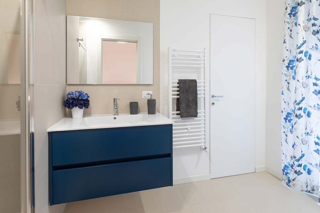 bagno moderno con lavabo da incasso colore blu con specchio rettangolare