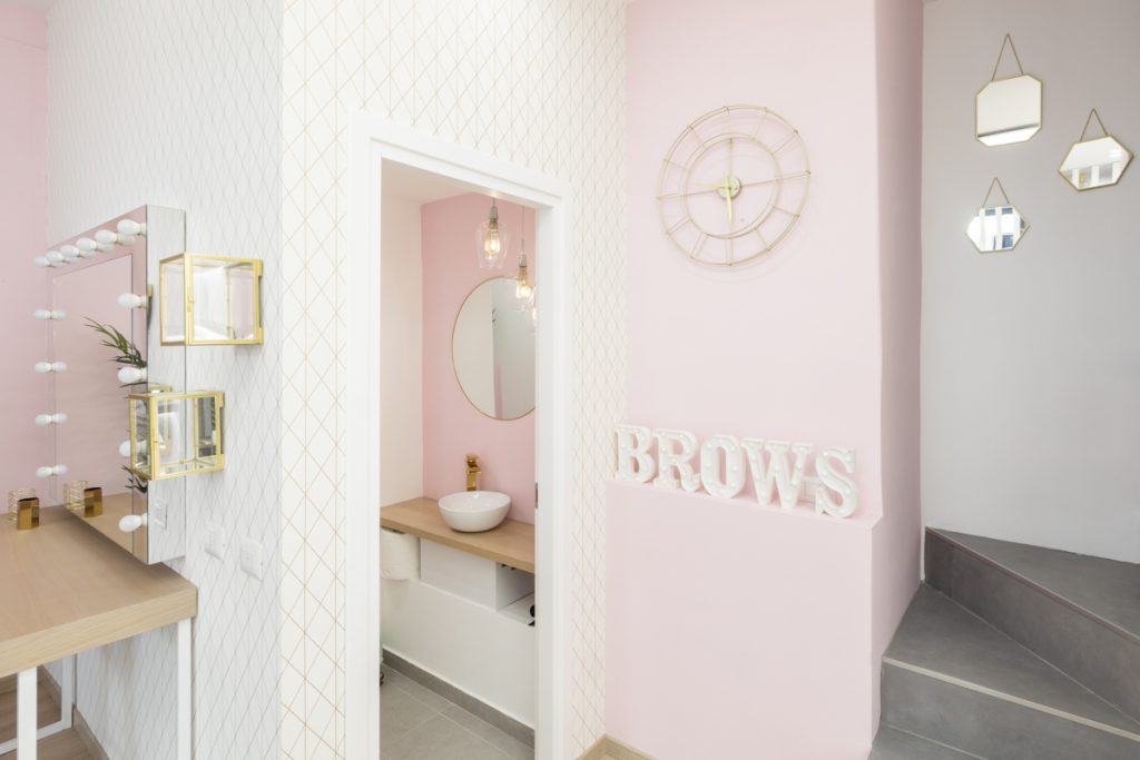 bagno moderno per centro estetico con lavabo d'appoggio bianco. Orologio contemporaneo su parete rosa.