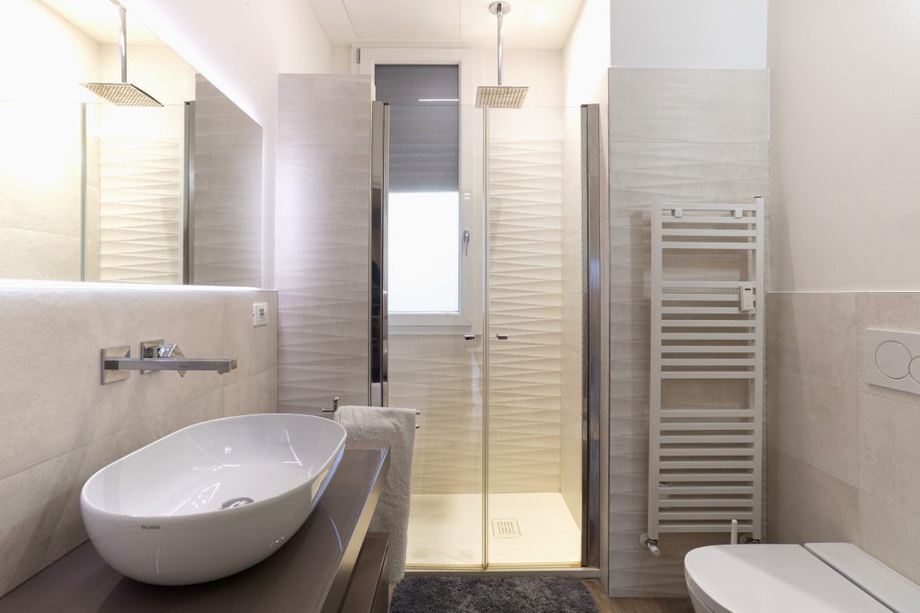 bagno moderno con doccia vetrata e rivestimenti con piastrelle a forma di onda.