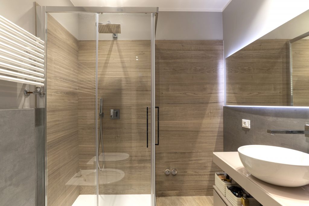 Bagno moderno con box doccia vetrato e rivestimenti in gres porcellanato.