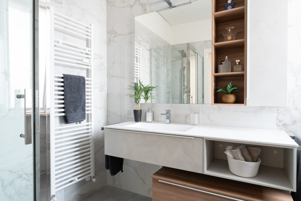 Bagno moderno con lavabo e mobile a sospensione. Rivestimento bagno con piastrelle effetto marmo venato bianco.