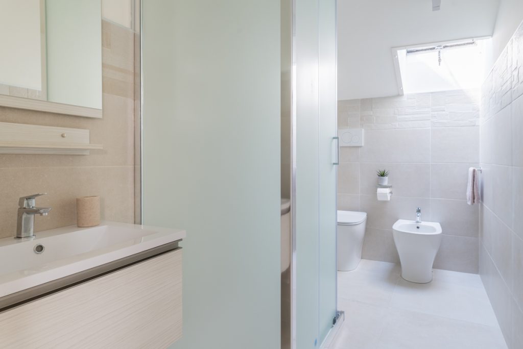 Bagno moderno con lavabo da incasso bianco e legno chiaro.