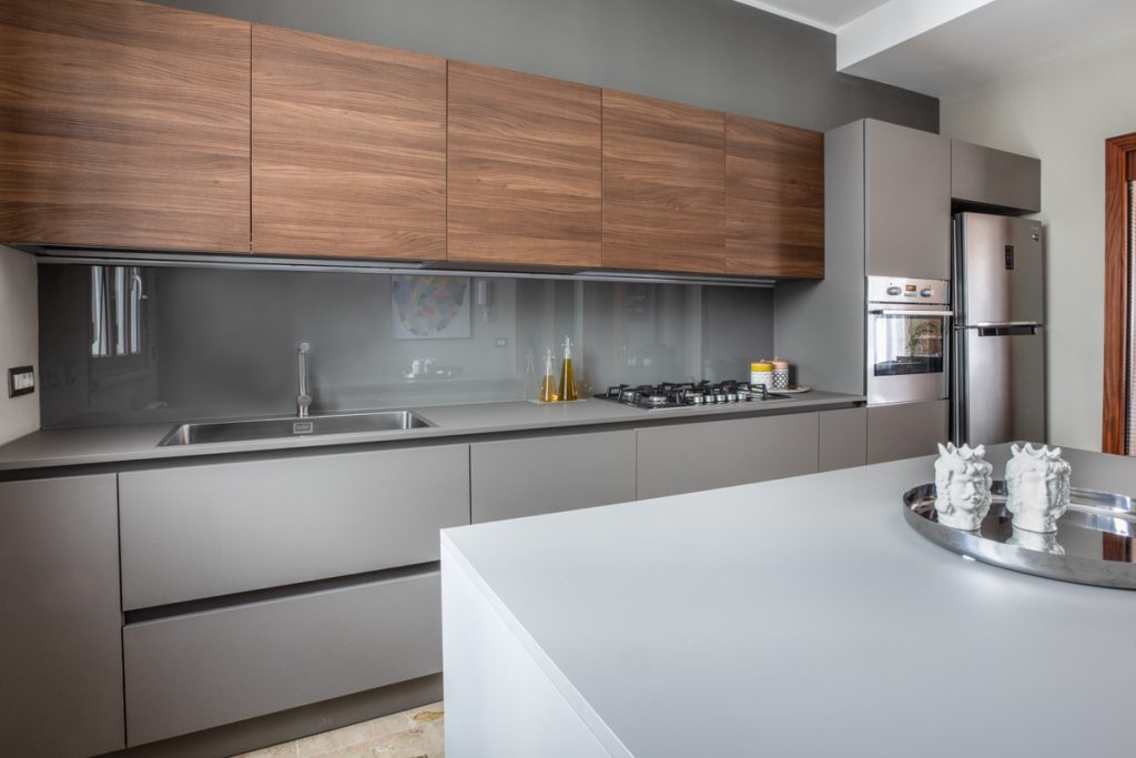 Cucina moderna con isola di colroe grigio con rivestimenti in legno scuro.