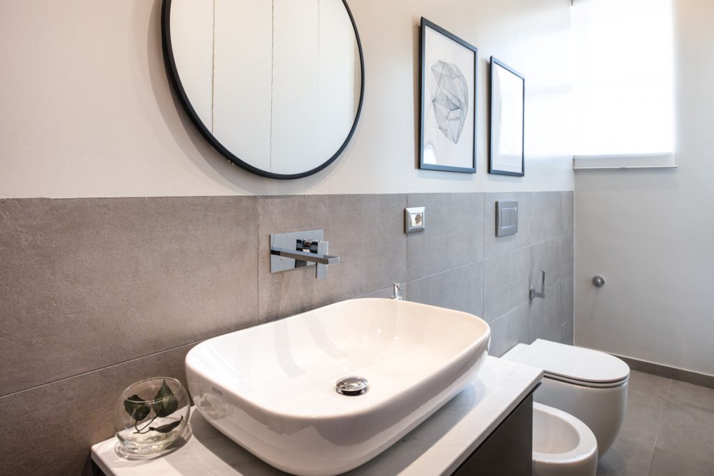 bagno moderno con lavabo d'appoggio dalla forma ovale su ripiano in marmo. sanitari moderni a sospensione.