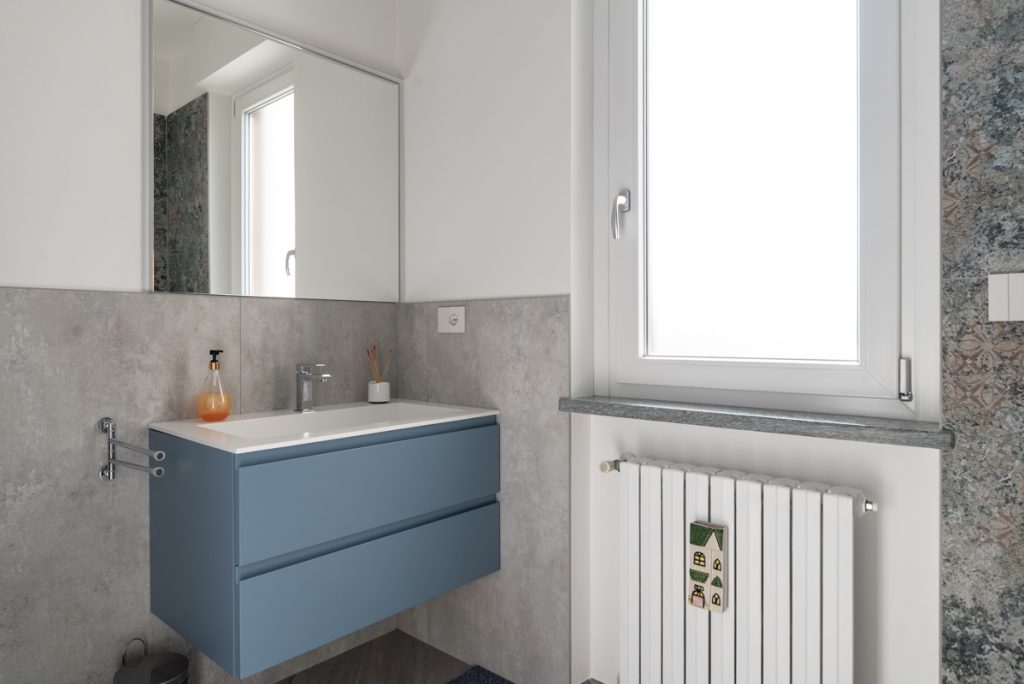 Bagno moderno con lavabo rettangolare a sospensione e specchio rettangolare.