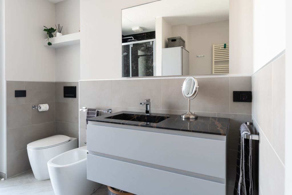 Bagno moderno con lavabo a sospensione con rivestimenti effetto marmo nero.