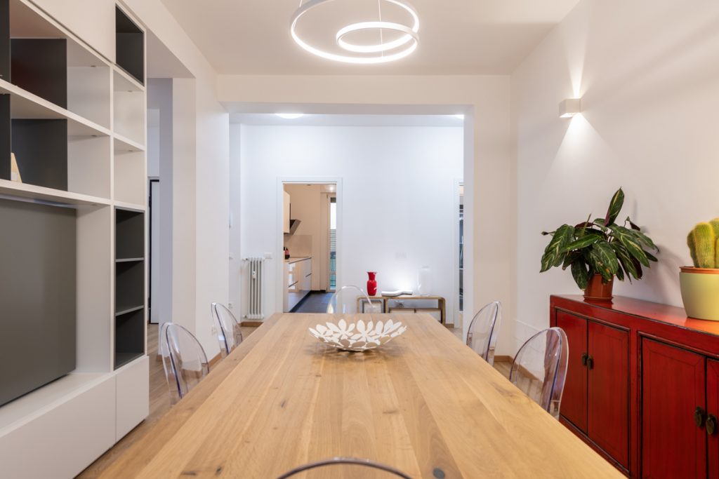 Tavolo da pranzo in legno con sedie trasparenti. Lampadario moderno a led.