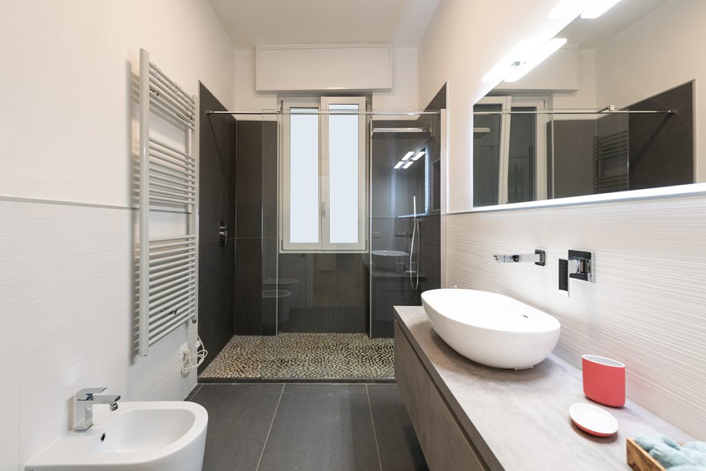 bagno moderno con gres porcellanato grigio e lavabo bianco a sospensione.