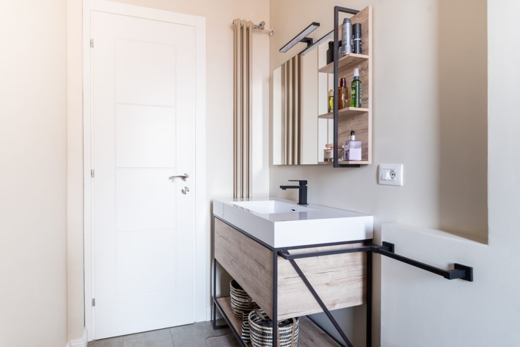 Bagno moderno con lavabo a sospensione bianco e in legno. Specchio rettangolare.