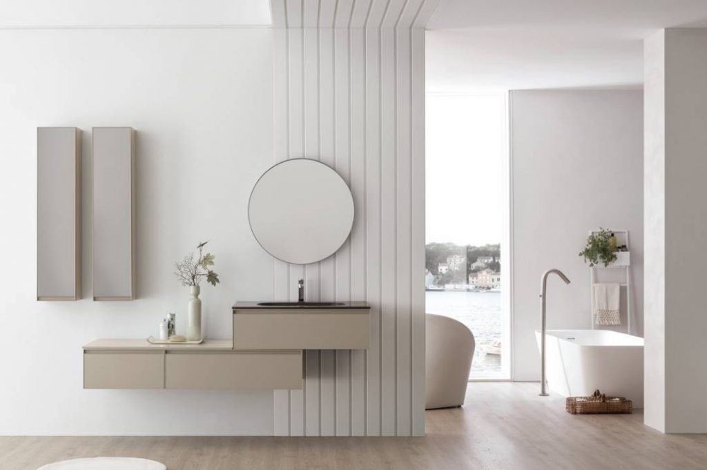 bagno minimal con specchio rotorndo e lavabo a sospensione.