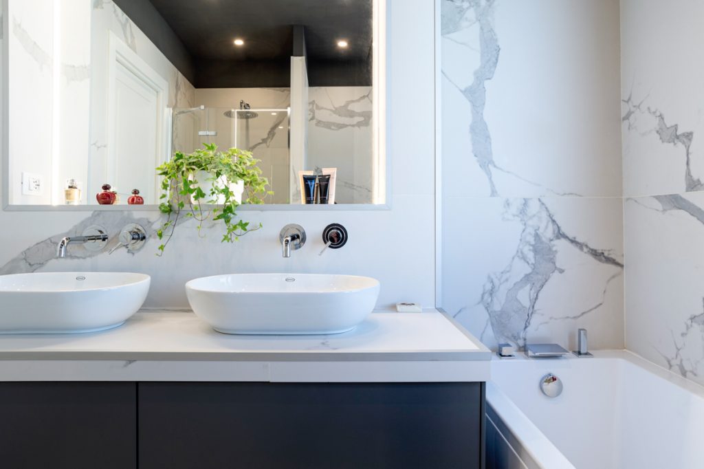 Bagno moderno con rivestimenti effetto marmo venato bianco.