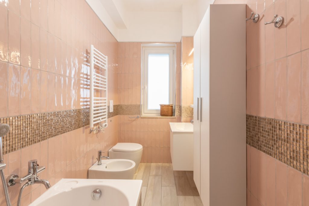 bagno elegante con piastrelle in mosaico rosa e oro.