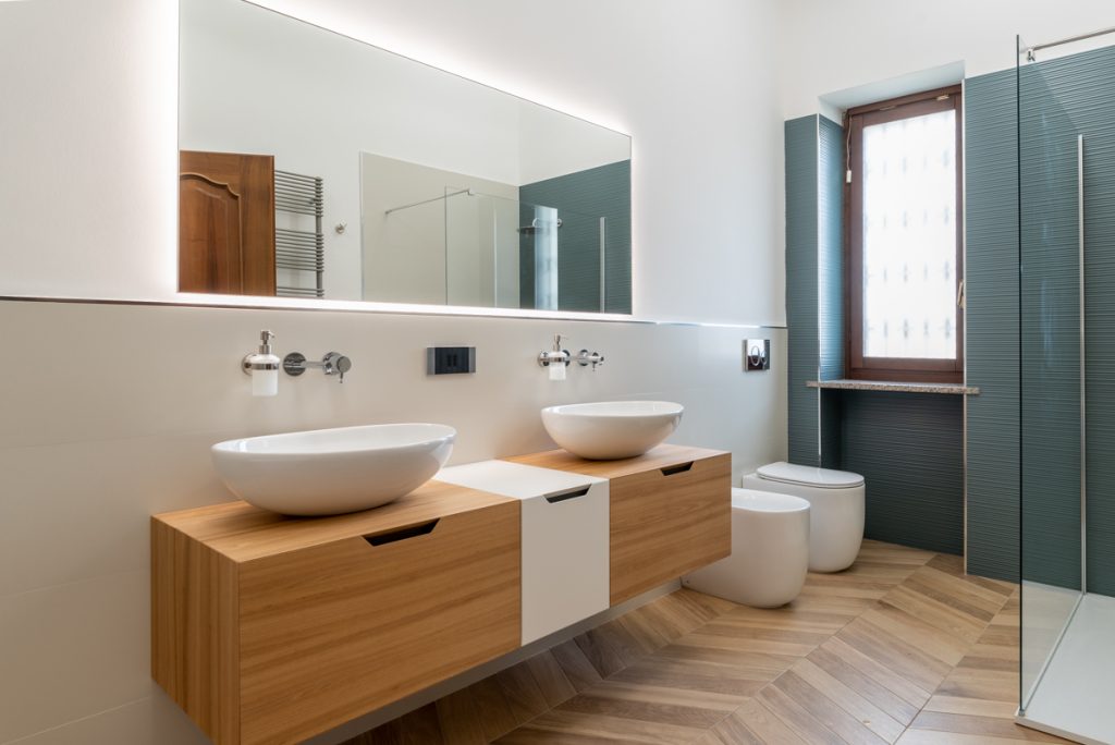 Bagno moderno con doppio lavabo d'appoggio su mobile in legno chiaro.