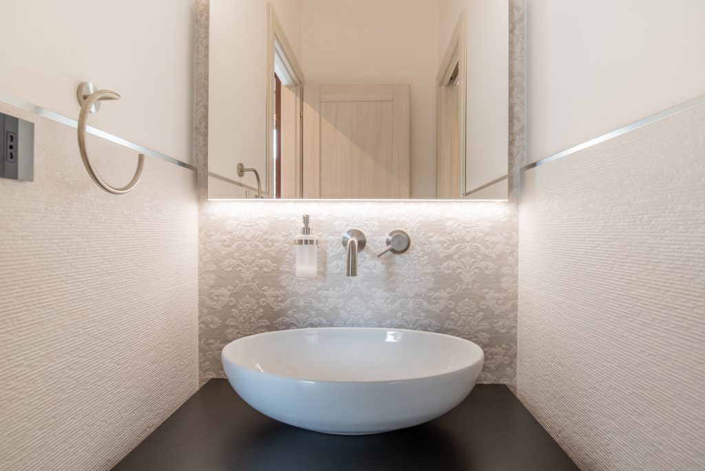 Bagno moderno con lavabo d'appoggio bianco e rivestimenti in gres.