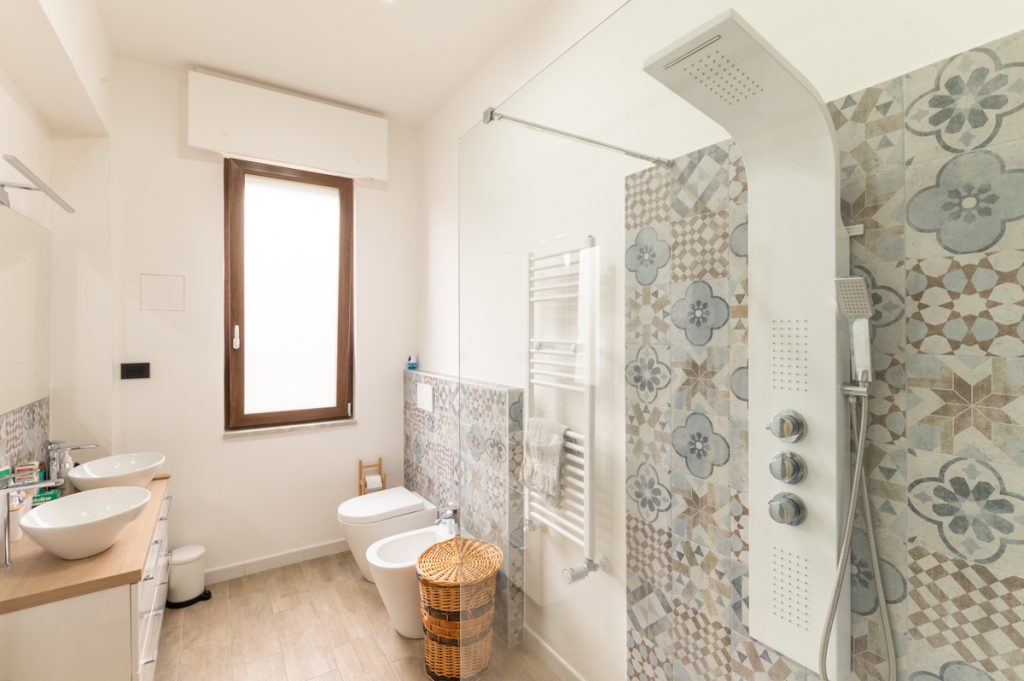 Bagno moderno con doppio lavabo d'appoggio e rivestimenti in cementine.