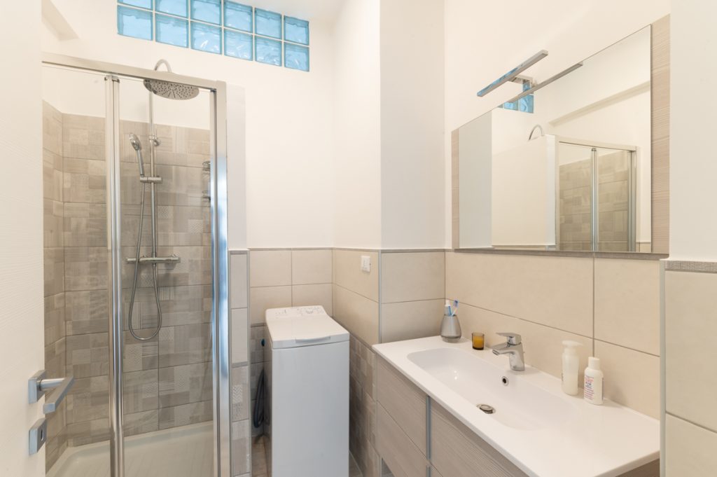 Bagno moderno con piastrelle in grès porcellanato e doccia con rivestimento in mosaico.