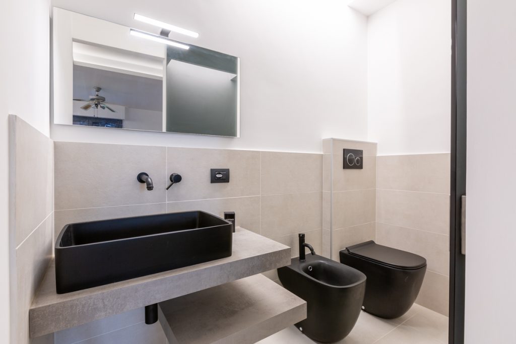 Bagno moderno con lavabo d'appoggio e sanitari neri.