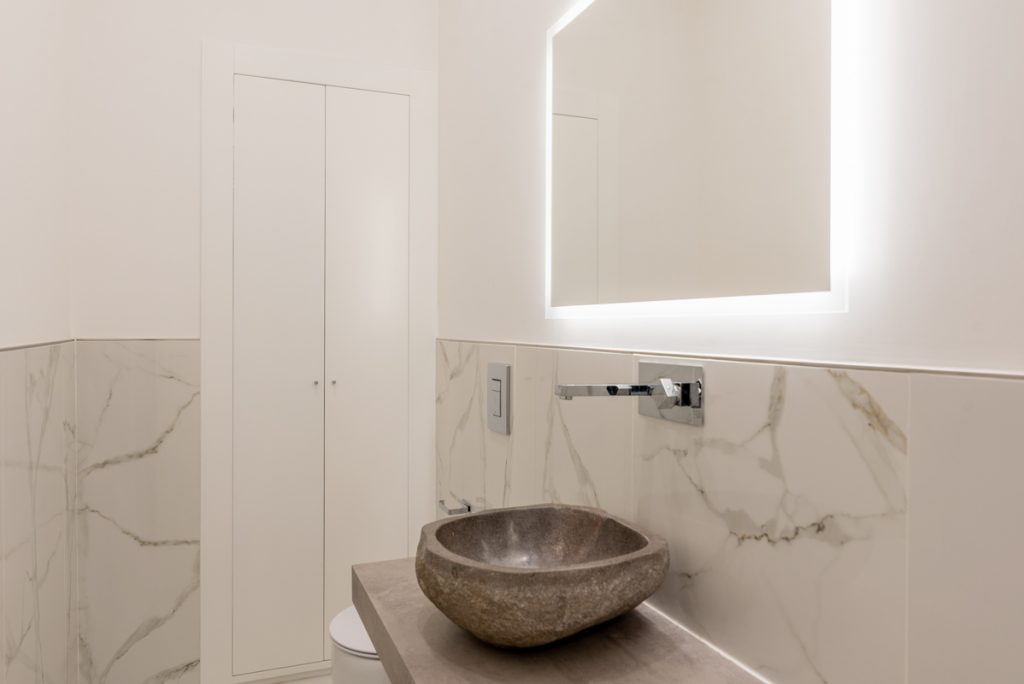 bagno moderno con rivestimenti effetto marmo e lavabo a sospensione effetto pietra naturale.