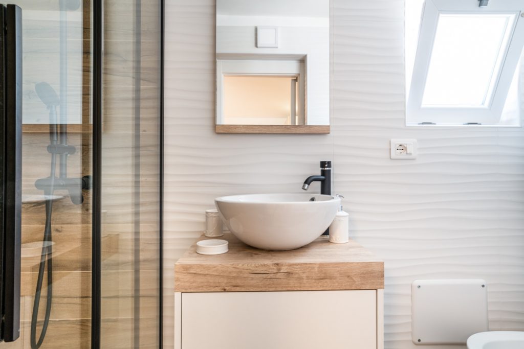 bagno moderno con lavabo rotondo d'appoggio su mobile in legno.