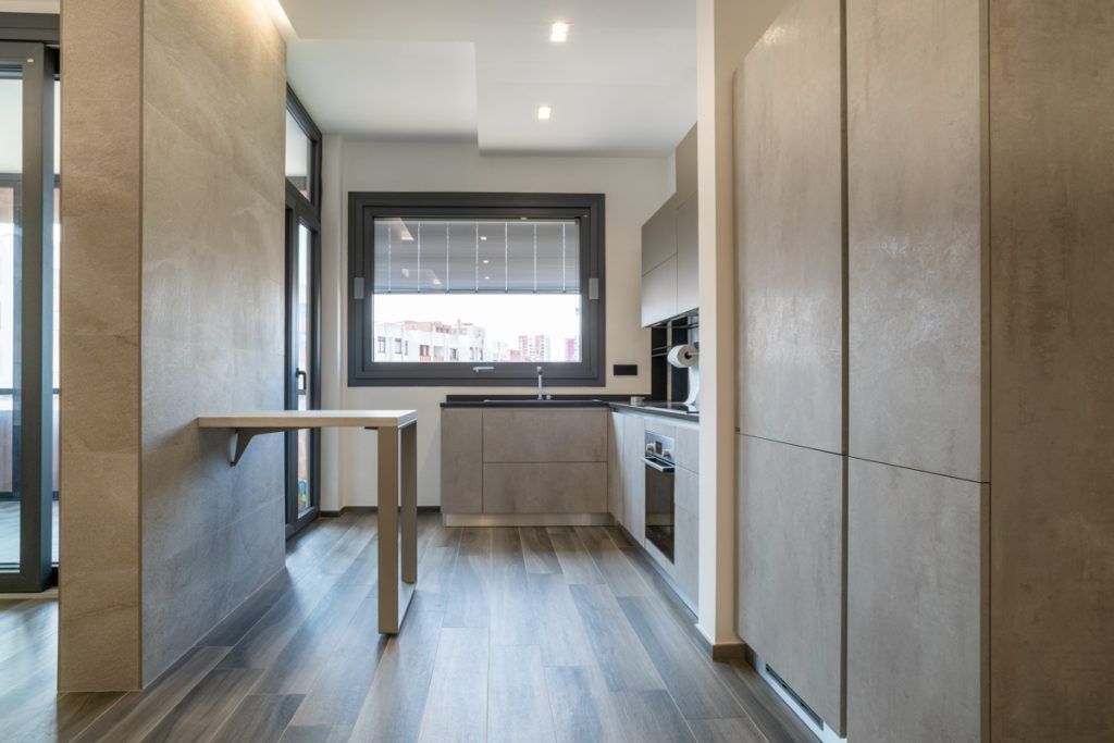 ristrutturazione appartamento taranto Cucina moderna con rivestimenti effetto pietra e top cucina nero.