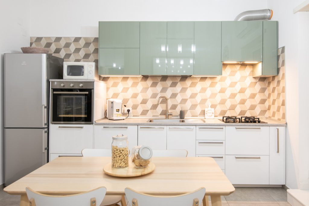 Cucina moderna con rivestimenti bianchi e verdi.