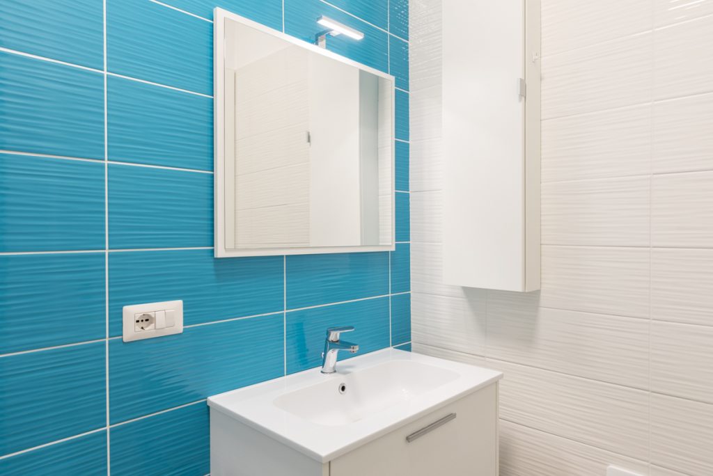 bagno con piastrelle azzurre e lavabo rettangolare.