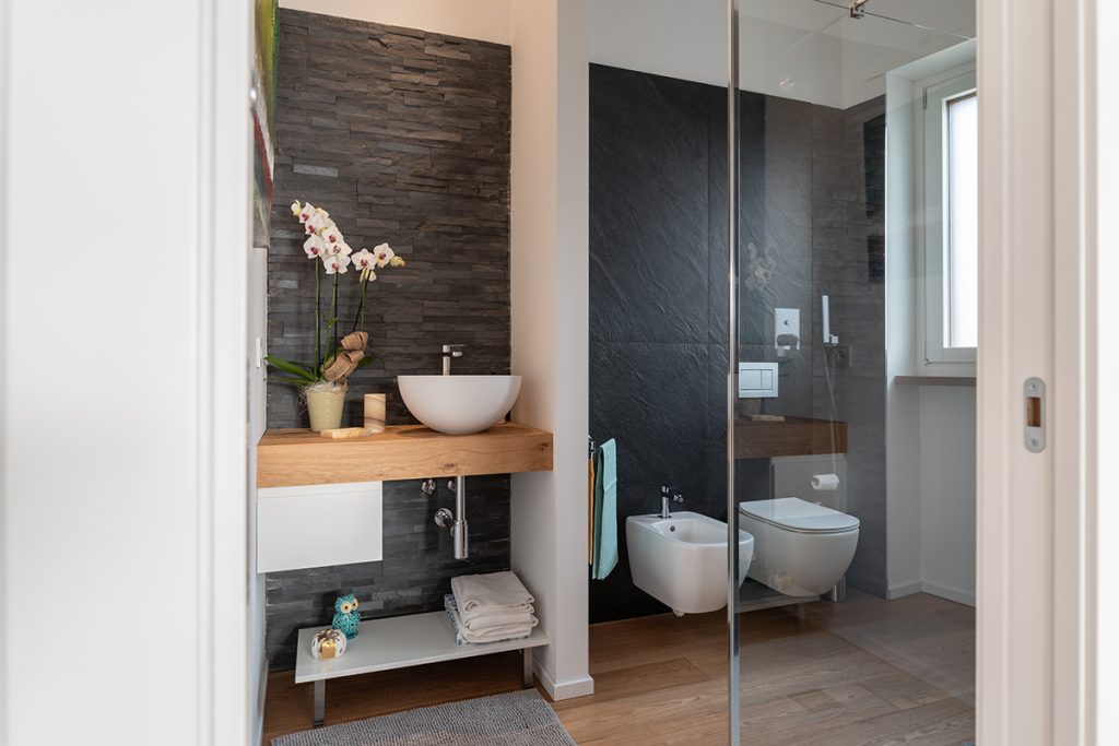 ristrutturazione casa torino Bagno con rivestimenti effetto pietra color antracite e lavabo d'appoggio.