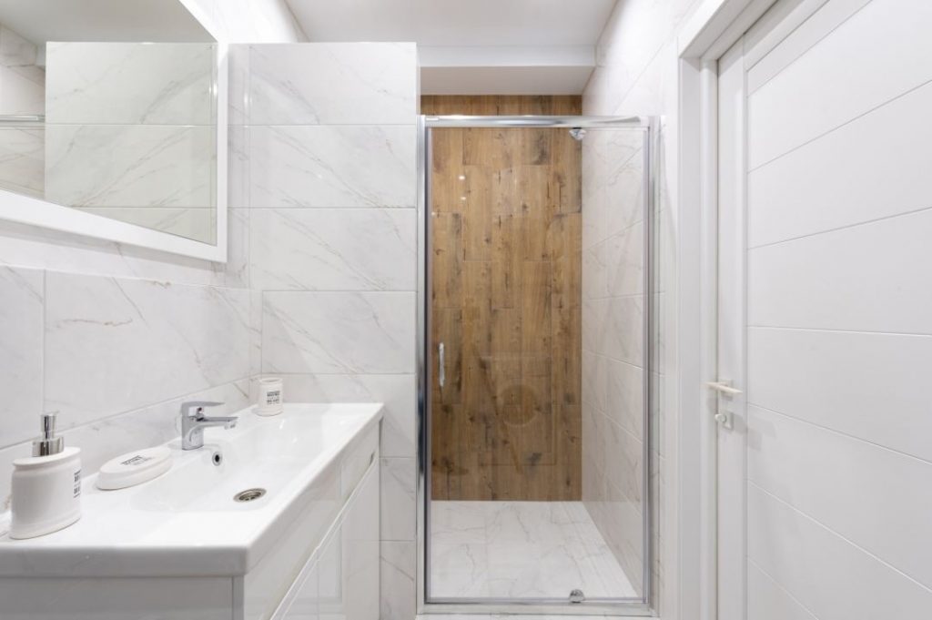 idee ristrutturazione bagno moderno con lavabo bianco rettangolare e rivestimenti doccia effetto legno.