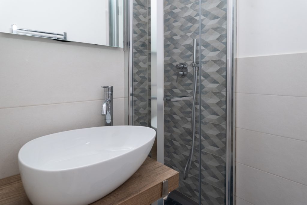 Bagno con rivestimenti per doccia con forma geometrica.