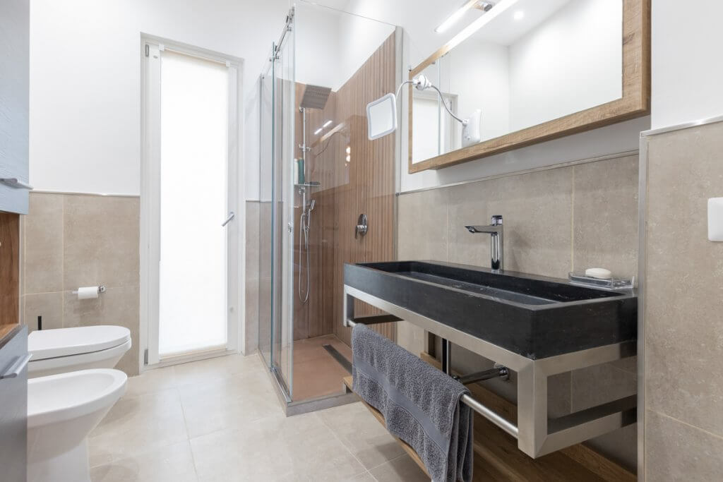 Bagno con lavabo a sospensione con rivestimenti effetto pietra.