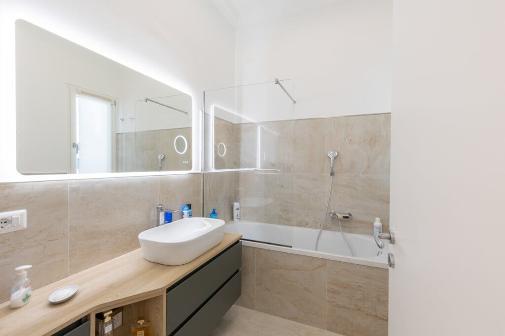 Bagno moderno con specchio retroilluminato e lavabo ovale d'appoggio