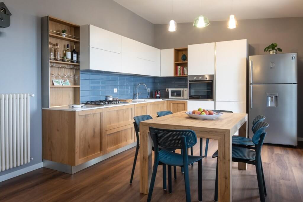 open space con cucina bianca e rifiniture in legno