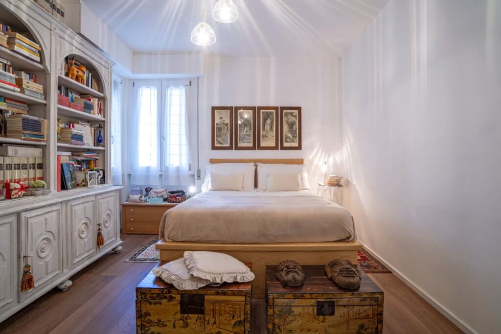 camera da letto con libreria shabby chic, parquet e bauli vintage di metallo