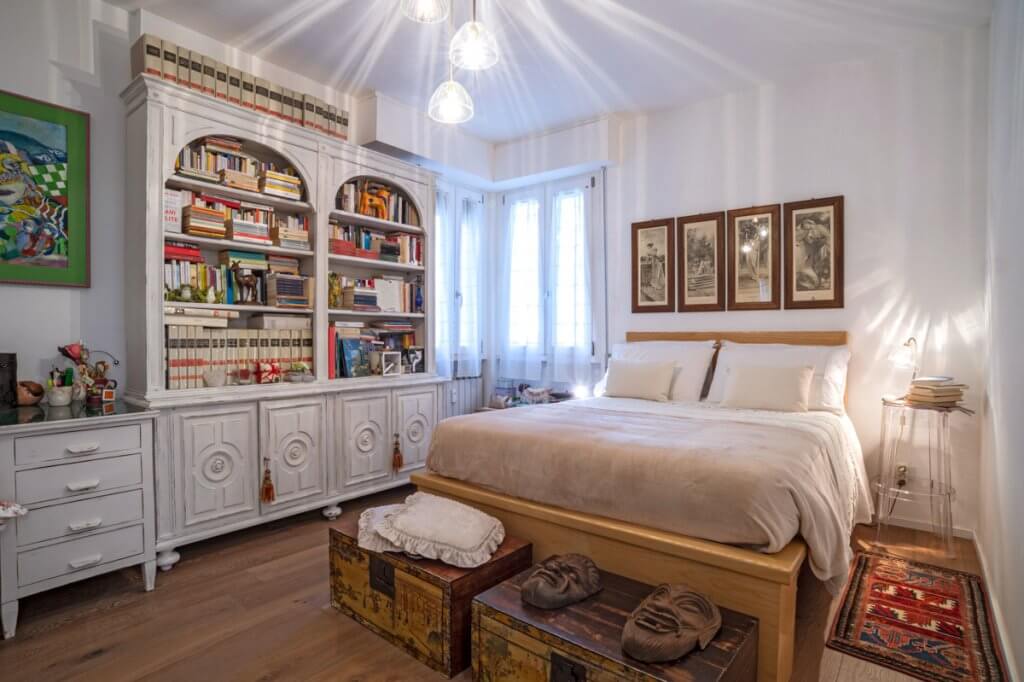 camera da letto con libreria shabby chic, parquet e bauli vintage di metallo