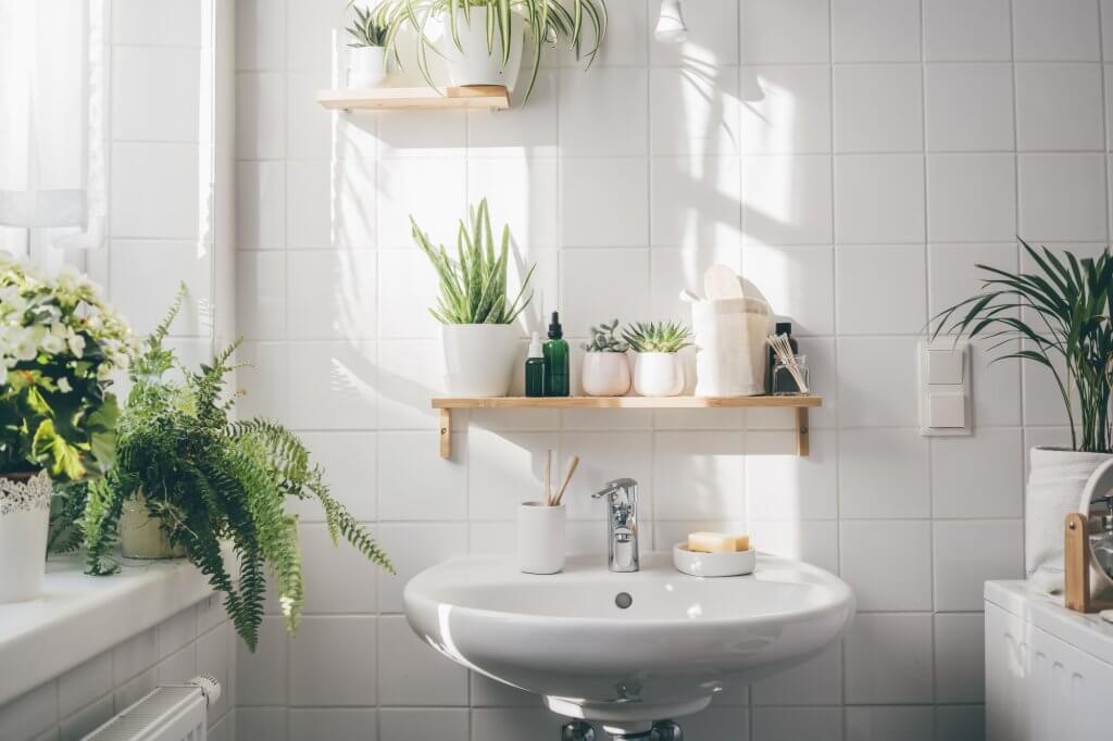 Bagno bianco con mensola in legno e piante