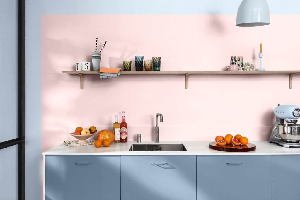 Colore pareti, interni casa. Cucina con frutta sul top di colore bianco, parete rosa e azzurra con mensola in legno