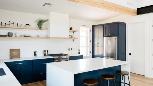 Cucina bianca con rifiniture blu e legno, con sgabelli e mensole