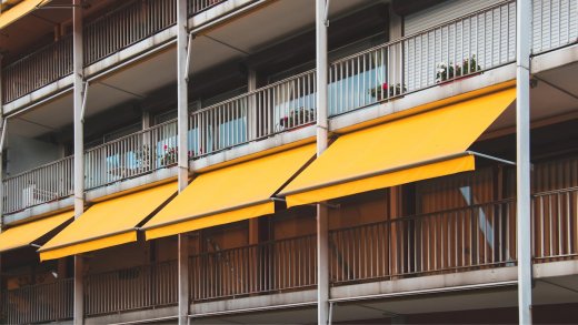 Balcone con tende da sole di colore giallo e vasi