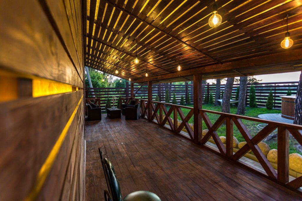 Veranda in legno con lampade con luce calda e giardino laterale