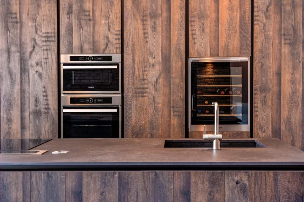 Cucina con rivestimenti in legno e lavandino, forno e frigo