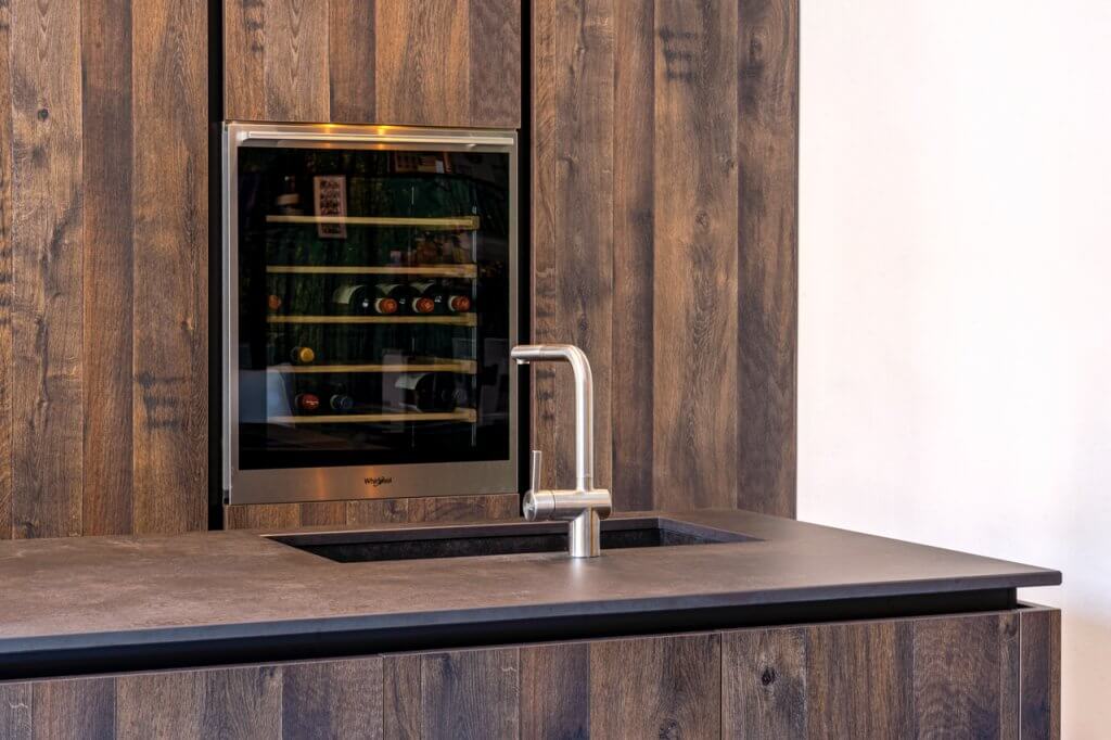 Lavandino della cucina con rivestimenti in legno, top in acciaio, frigo