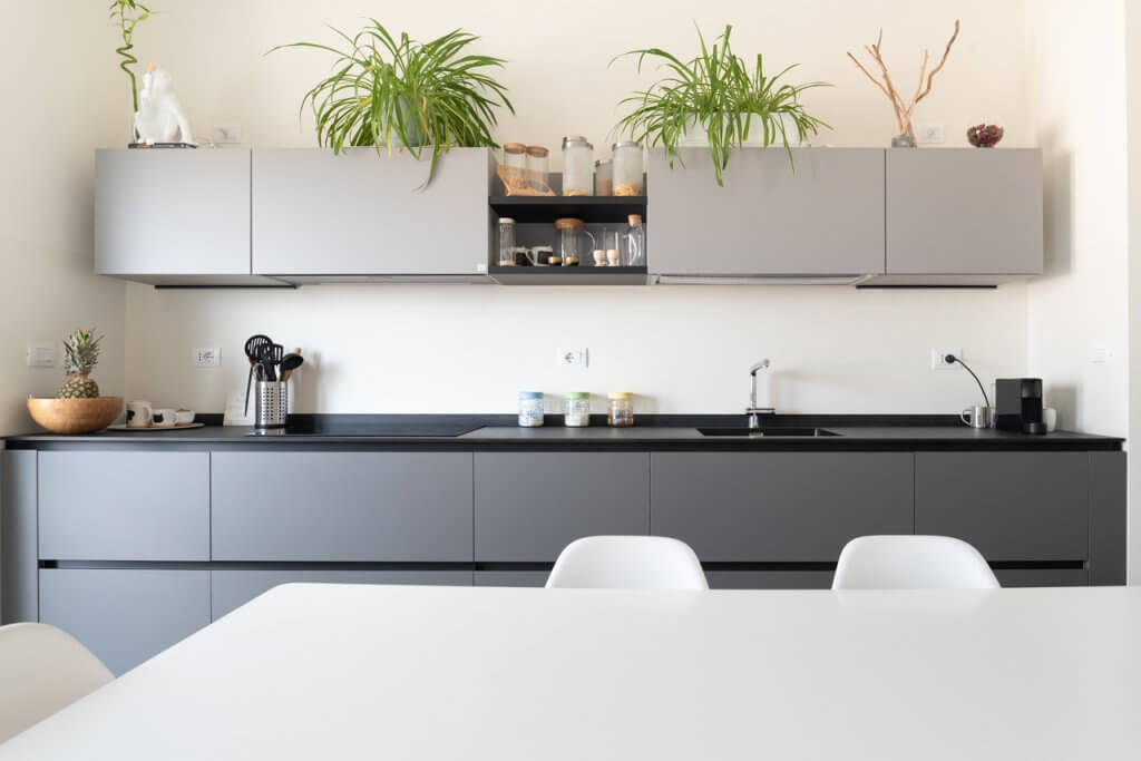 Cucina stile moderno con top nero, rivestimenti in laccato grigio e tavolo bianco