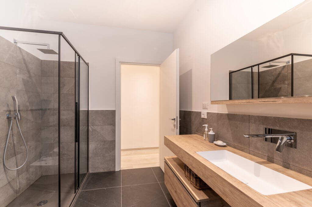 Bagno con lavabo sospeso in rivestimenti in legno, box doccia walk in