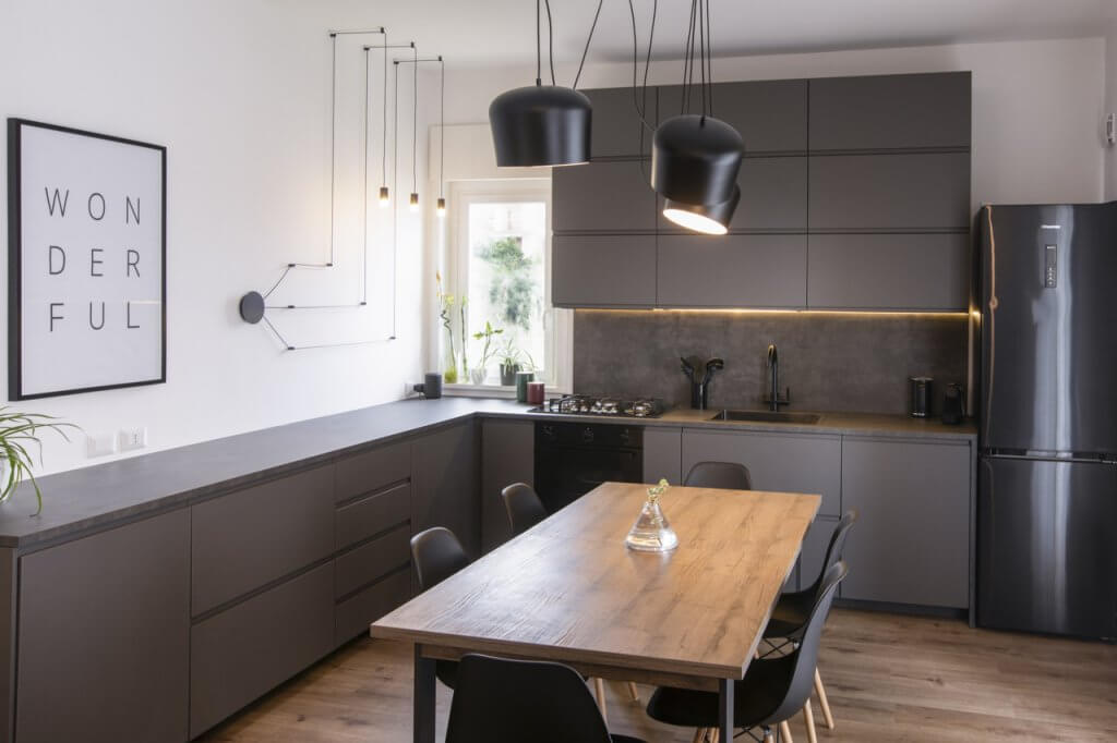 Cucina con rivestimenti in legno, colore nero, lampade dal design moderno e illuminazione al led