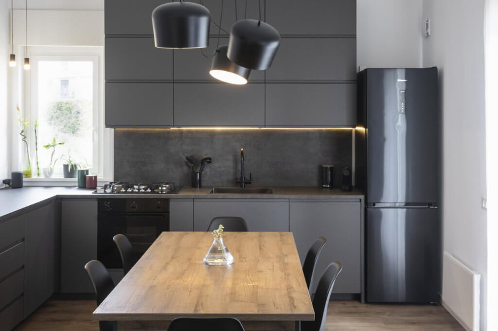 Cucina con rivestimenti in legno, nero, illuminazione al led, frigo, lampade dal design moderno