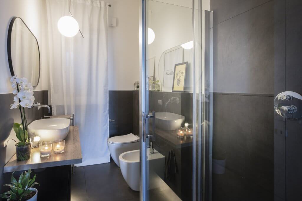 Bagno con rivestimenti in gres, lampada, specchio, lavandino e sanitari dal design moderno