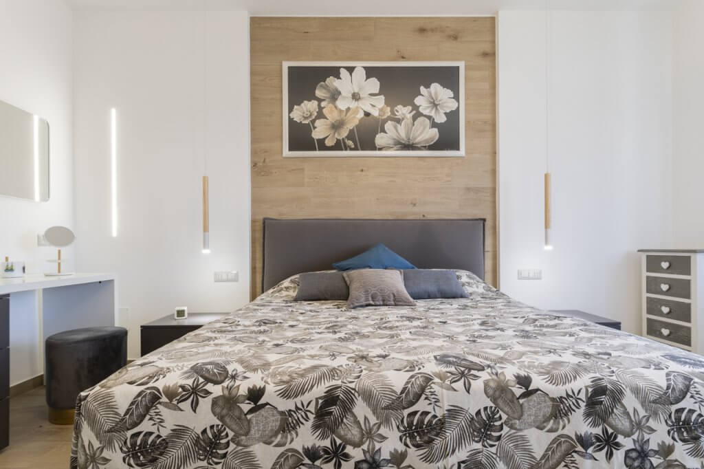 Camera da letto con rivestimenti in legno, parete bianca, lampade sospese dal design moderno